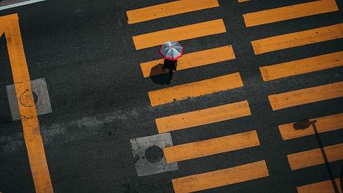 tarmac bird's-eye photography of person walking on pedestrian lane road