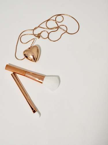makeup gold heart pendant necklace and two gold handled makeup brushes gold