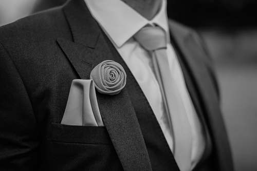 suit greyscale photo of man wearing peak lapel suit jacket clothing