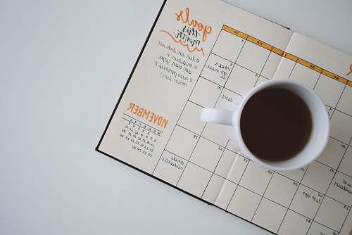 goal white ceramic mug with coffee on top of a planner journal
