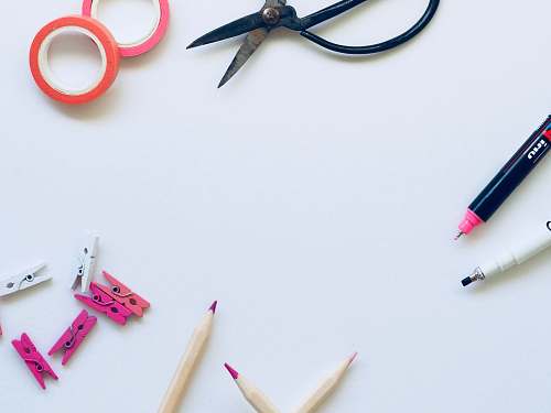 pencil black scissors near brown pencils on top of white textile background