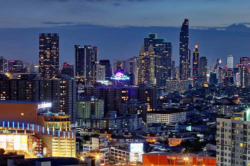 city aerial photography of city with high-rise buildings viewing mountain during night time town
