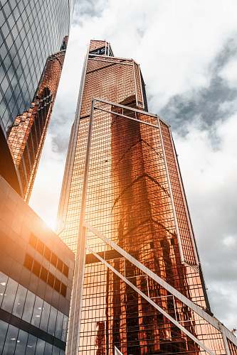 city gold high-rise building under cloudy sky urban