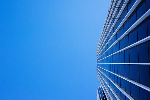 blue low-angle photography of curtain glass building under blue sky downtown
