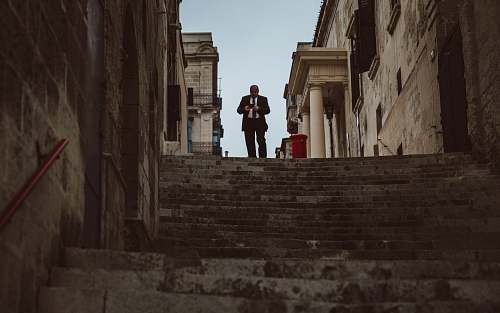 architecture man walking downstairs between concrete buildings alley