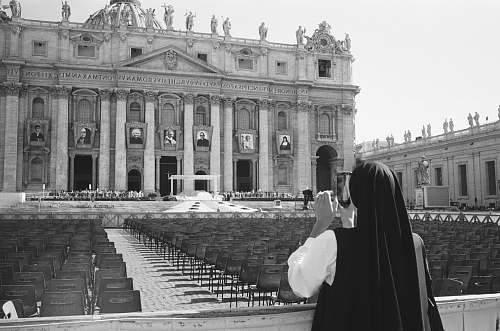 black-and-white nun taking photo of building architecture