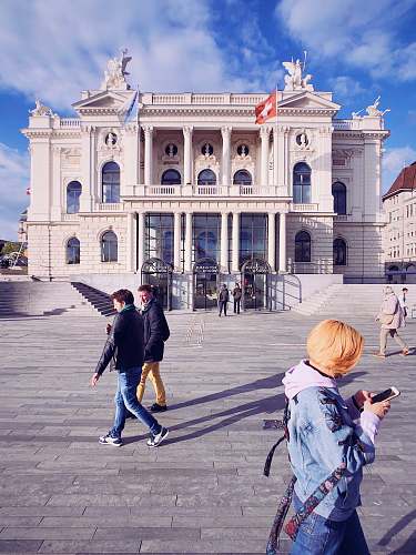 human people beside white building during daytime person