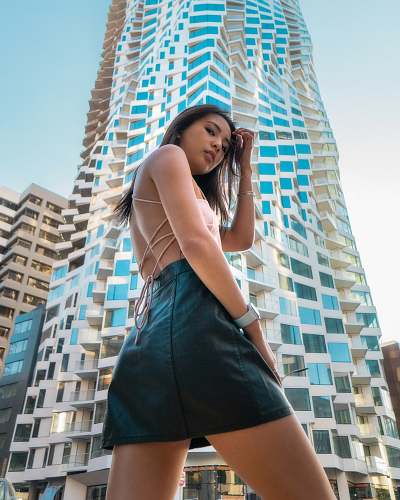 city woman wearing beige backless blouse and black leather miniskirt walking on street urban