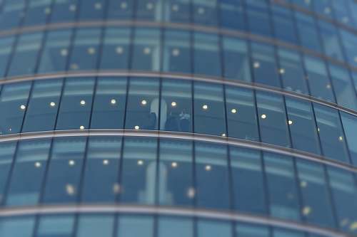 building selective focus photograph of person standing near building glass curtain grey
