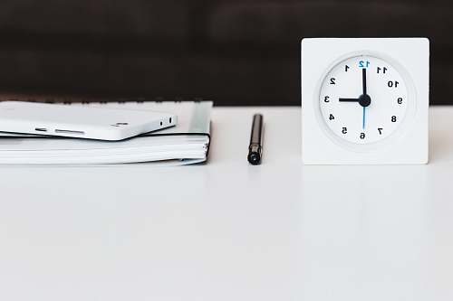 grey white desk clock near pen and book black-and-white