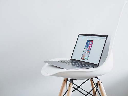 laptop turned on MacBook on top of white chair computer