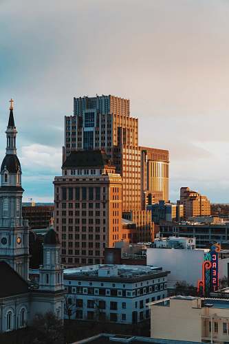 building city with high-rise buildings under blue and white sky during daytime office building
