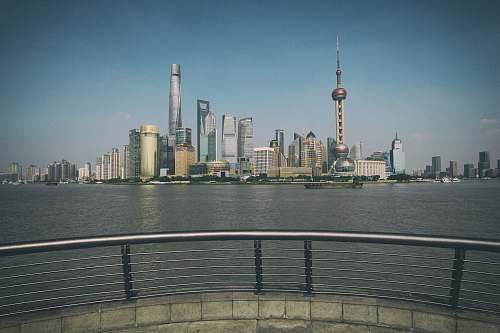 railing concrete buildings beside sea during daytime metropolis