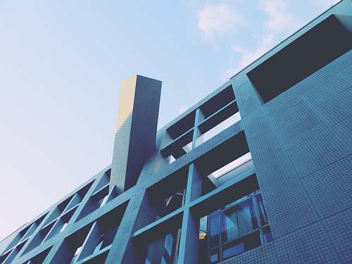 building low-angle photography of blue high-rise building under blue and white sky during daytime office building