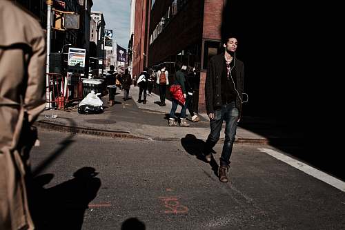 person man walking on road using earbuds people