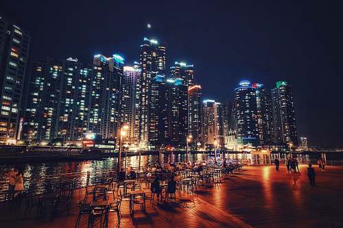 building people beside the river with buildings at the distance during nighttime town