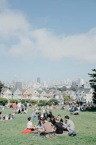 building people sitting on grass field during daytime downtown