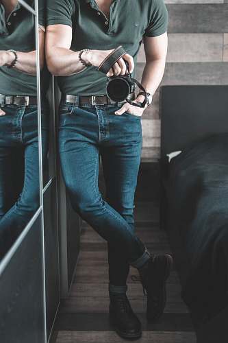 apparel man holding DSLR camera inside room pants
