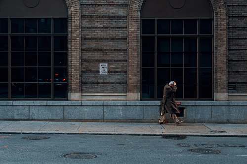 apparel person standing beside building during daytime human