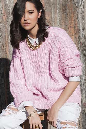 apparel women in pink knitted sweater sitting by woode wall sleeve