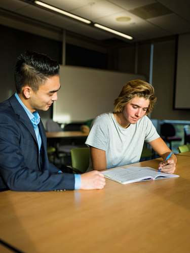 person two men sitting beside table with opened book human