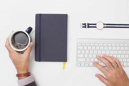 work person holding black mug filled with black liquid desk