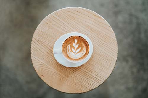 drink cappuccino on white ceramic mug with saucer on round brown coaster beverage