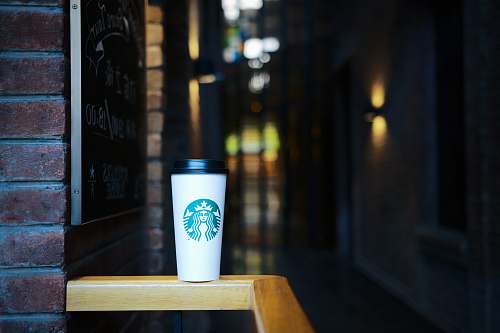 brick Starbucks coffee on top of wooden rail blackboard