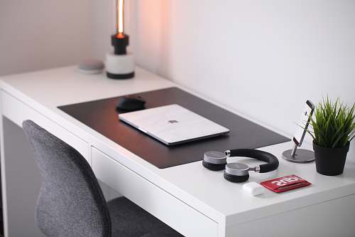 pot gray laptop on desk beside headphones table