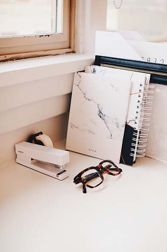 work white stapler and eyeglasses with brown tortoiseshell frame on desk office
