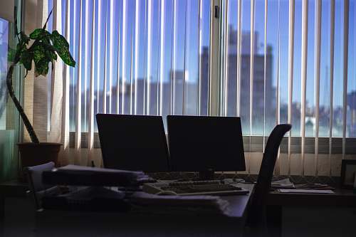furniture two black flat screen monitors on desk near window lcd screen