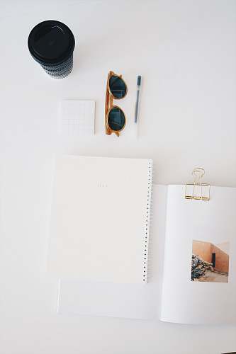 glasses flat lay photography of paper, sunglasses, cup, and pen notebook