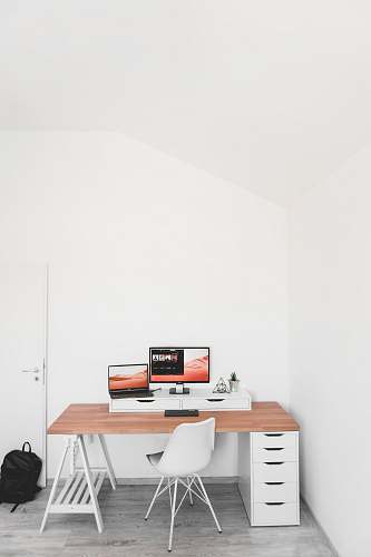 chair turned on flat screen monitor and laptop on desk table