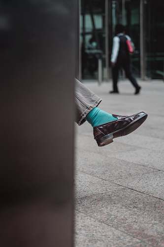 shoe person showing unpaired brown leather dress shoe street
