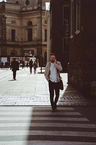 person man holding phone while standing on pedestrian lane people