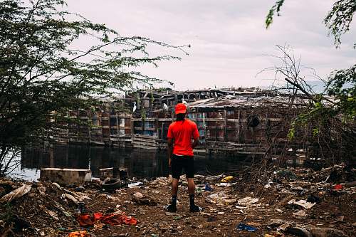 person man in red shirt facing house building