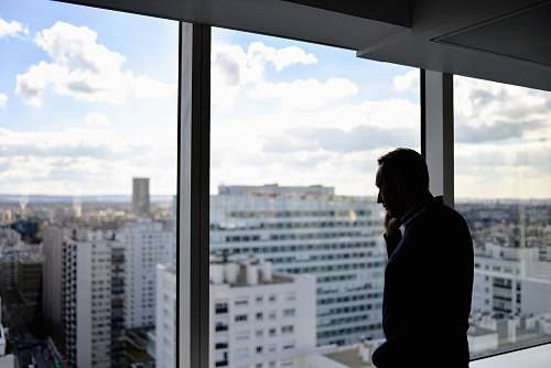 person man standing beside glass window paris