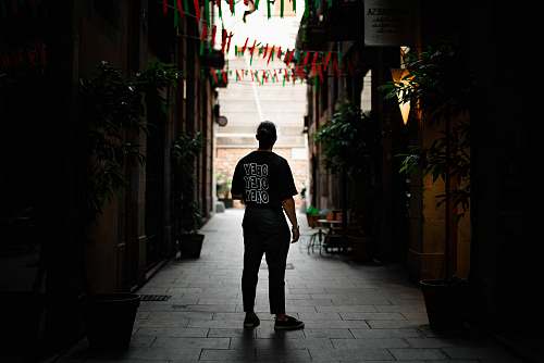 person man standing in alley between buildings people