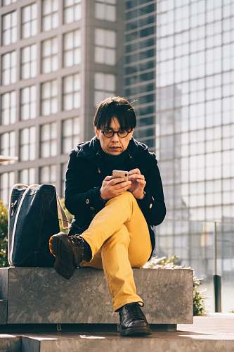 person man using smartphone sitting on concrete bench people