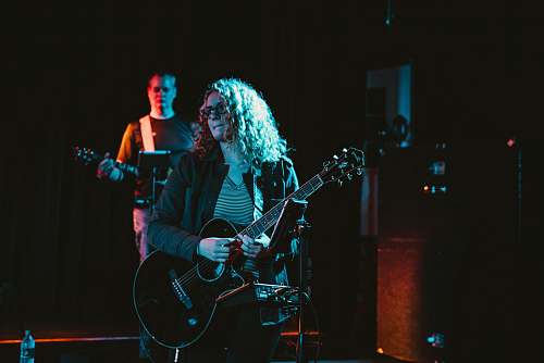 person person in black blazer playing Les Paul guitar performing on stage people