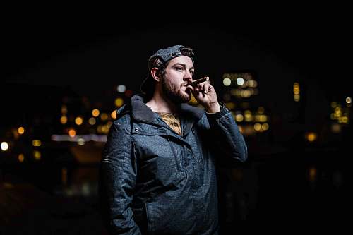 person standing man in black zip-up jacket smoking face