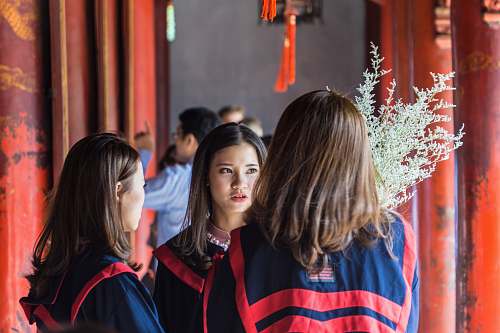 person three women having conversation inside building academic gown
