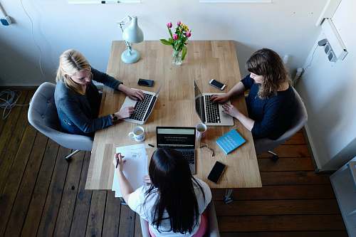 furniture three women sitting around table using laptops table