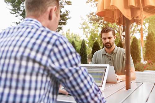 person two person sitting on patio table using laptop computer people