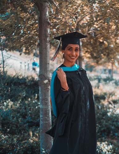 person woman in black and blue academic dress smiling graduation