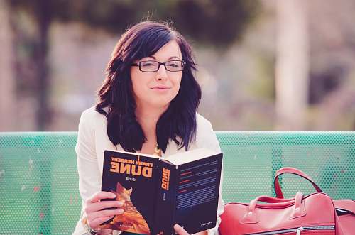 people woman reading book while sitting on green bench book