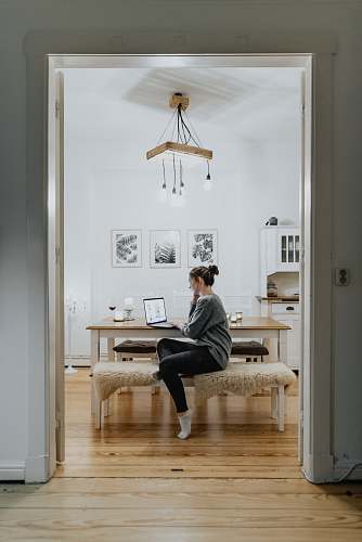 person woman sitting on ottoman while leaning on table flooring