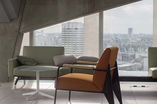 chair orange fabric padded armchair with black metal base near round clear glass-top table and gray sofa furniture