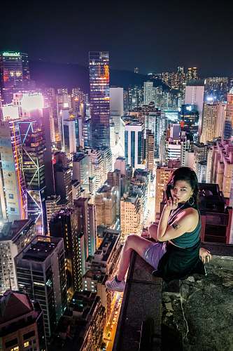 nature woman sitting on a terrace overlooking an urban city at night outdoors