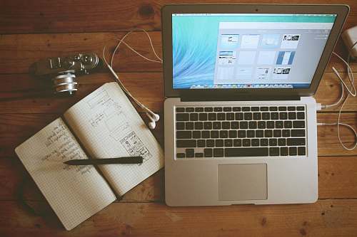 computer turned on MacBook Air beside white notebook wood